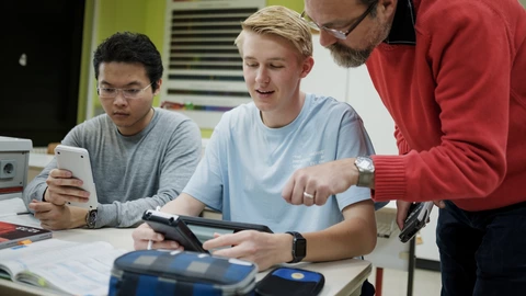 Lehrkraft und 2 Schüler bei der Arbeit mit digitalen Medien